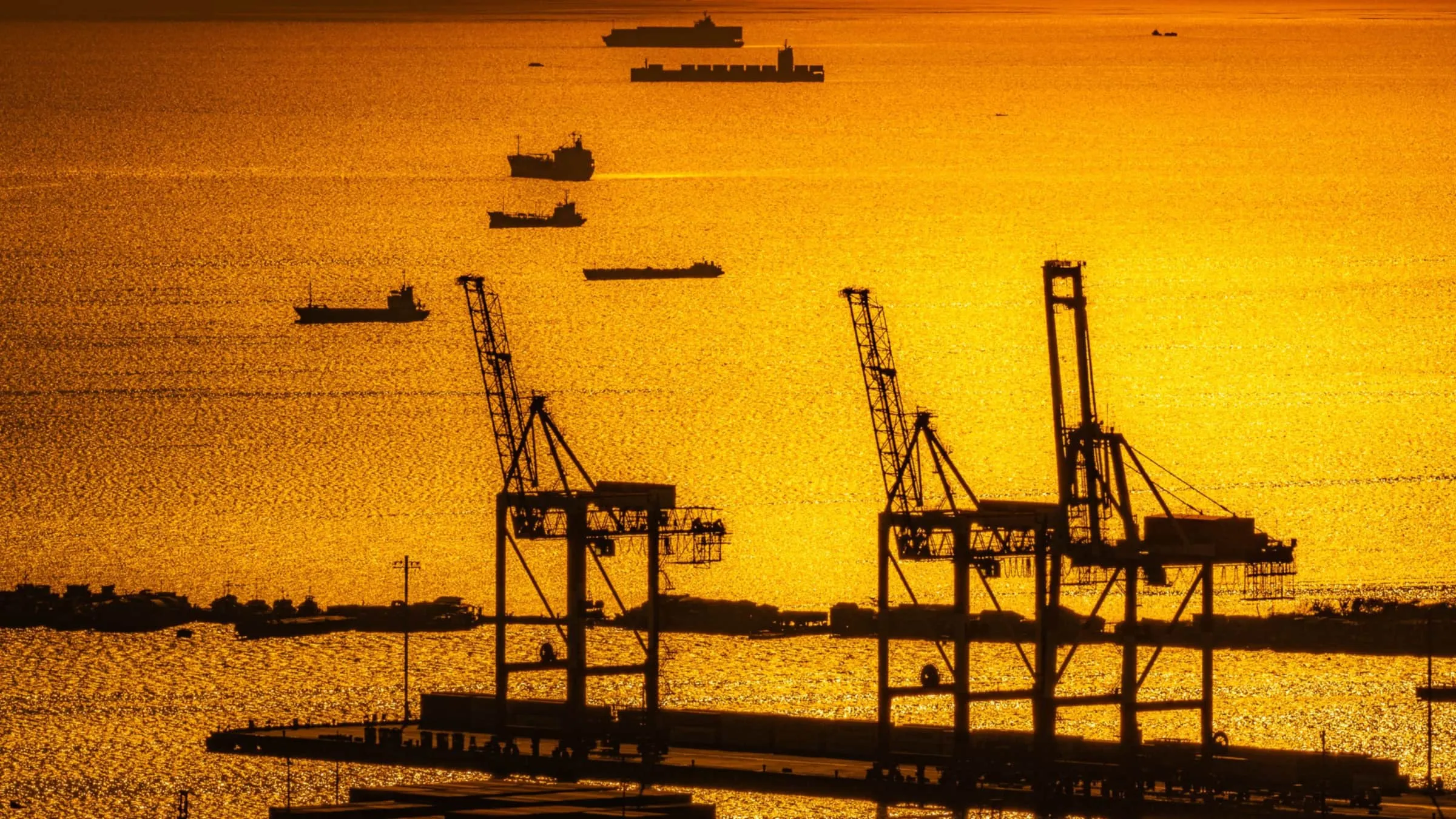 Port cranes and cargo ships at sunset