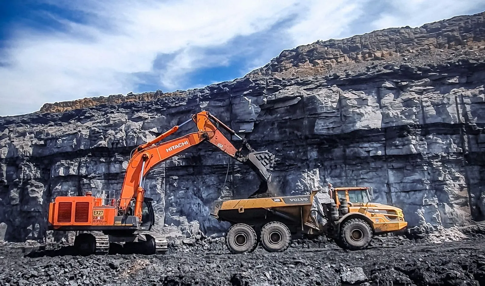 An excavator loading a dump truck at an open-pit mine